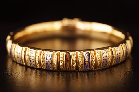 A bangle of 14k gold set with blue enamel