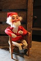 Old shop Santa in felt clothes and clogs sitting in an old wicker chair...