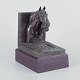 L'Art 
præsenterer: 
Jeanne 
Patricia 
Rynhart 
(1946–2020), 
irsk 
billedhugger.
Bogstøtte i 
bronze på 
træsokkel.
