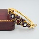 Armring af 18 
kt. guld prydet 
med opal, rubin 
og emalje, ...