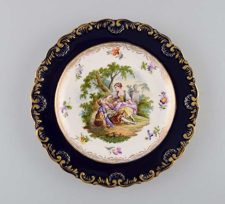 Antik Meissen tallerken i håndmalet porcelæn. Romantisk scene, blå kant med 
gulddekoration. Sent 1800-tallet.
