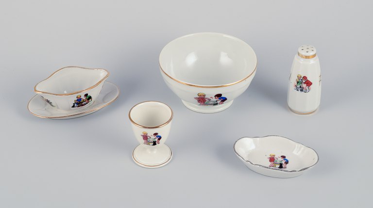 Frankrig børneservice i porcelæn bestående af: Skål, æggebæger, peberbøsse, 
miniature sauceskål og en lille oval skål. Motiver af børn i leg.