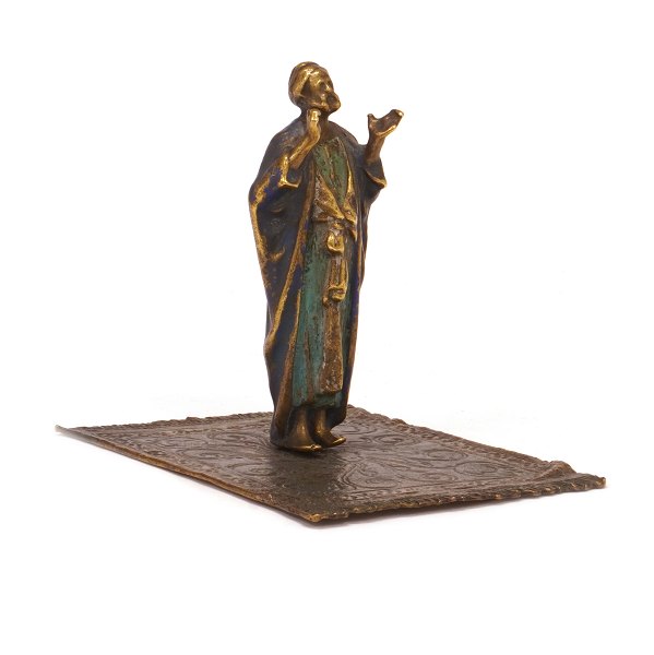 Figur einer orientalischen Person auf einem Teppich. Zinn, dekoriert. H: 9,5cm. 
Base: 9x11cm